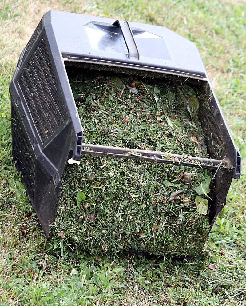 An electric push mower with a full grass catcher bag on a lawn
