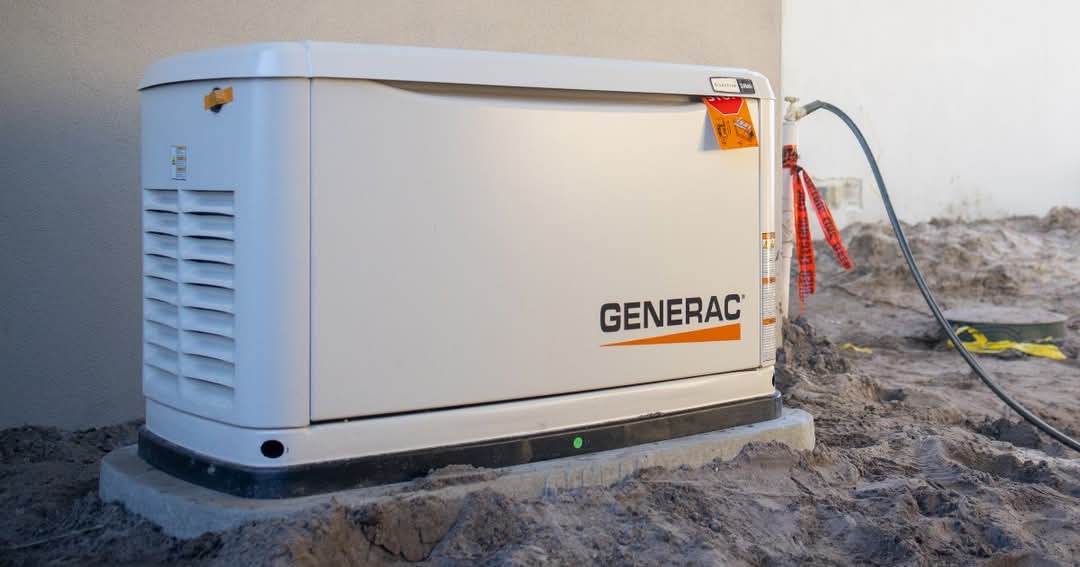 A whole-home standby generator installed on a concrete pad beside a house
