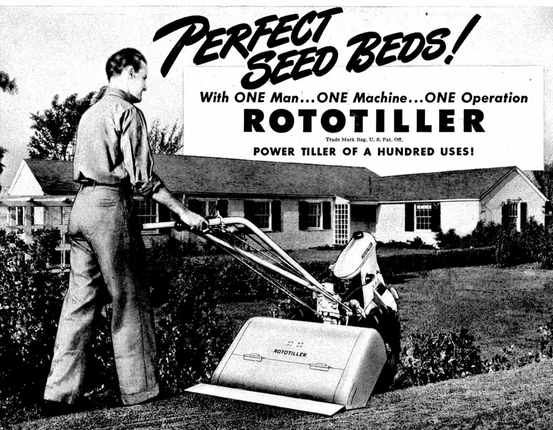 A gas tiller with visible tines standing on tilled ground