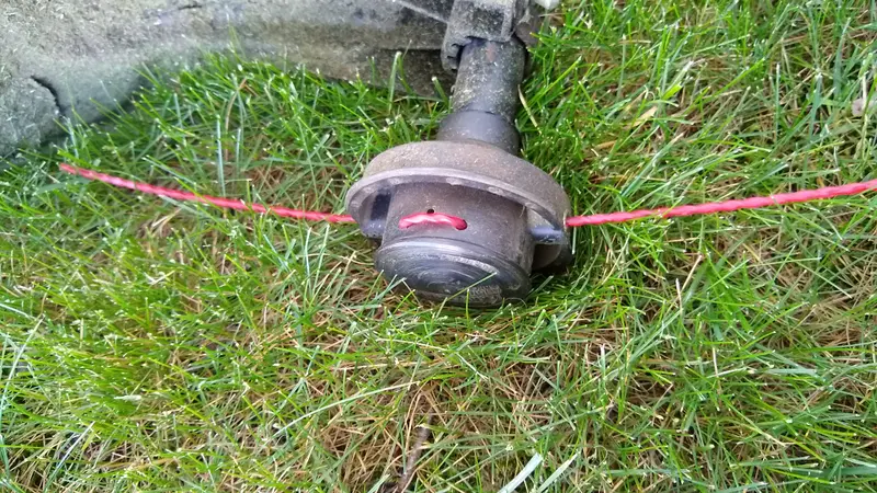 Close-up of a string trimmer head with the nylon cutting line